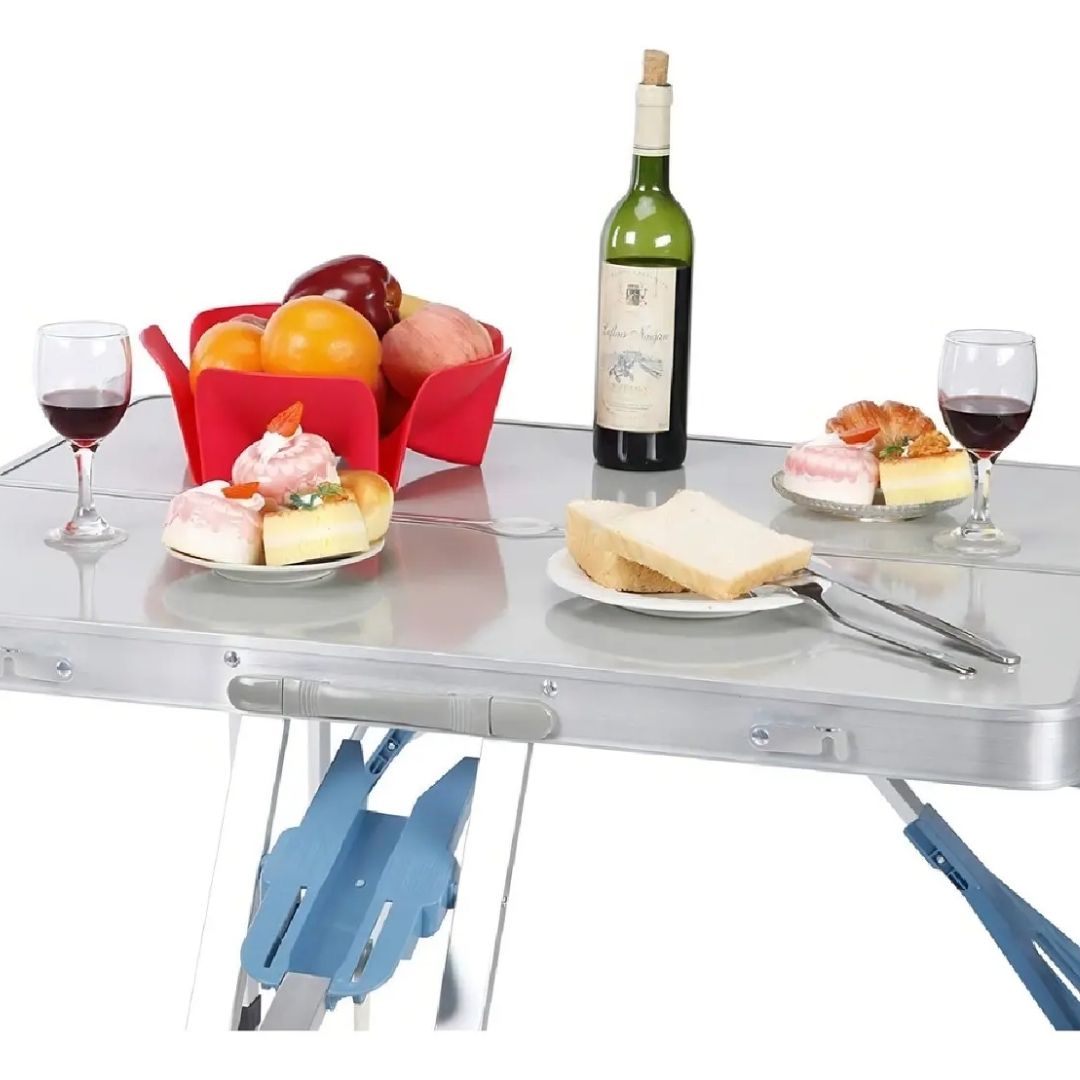 Mesa de aluminio plegable con alimentos, copas de vino y frutas servidas sobre su superficie.